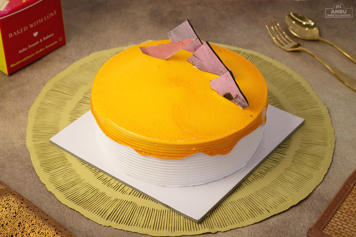 Yellow cake Butterscotch with a pink heart on a green placemat, surrounded by gold cutlery and a red box.